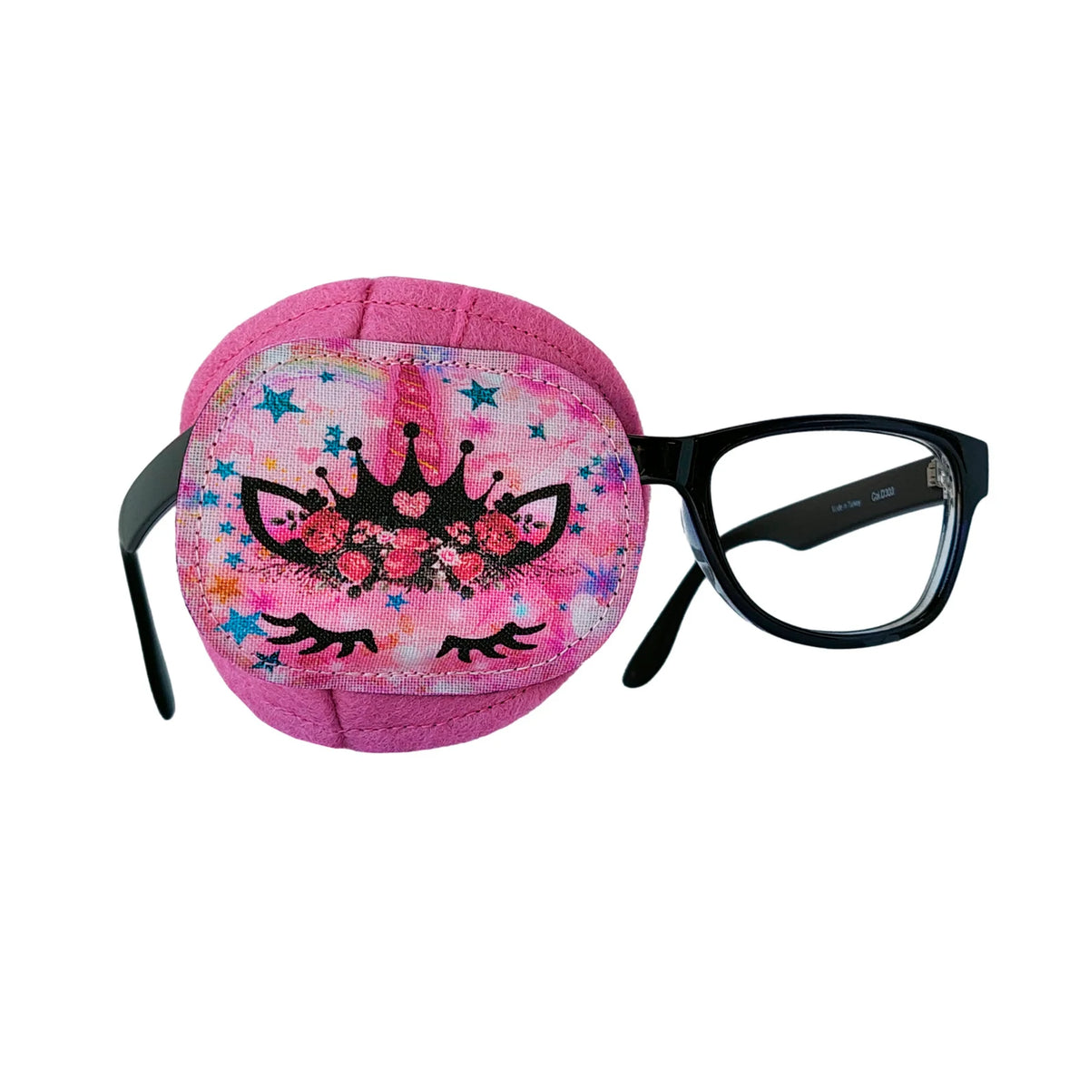 Pink wool felt eye patch with black crown, cat-eye details, and colorful stars, shown on black-framed glasses